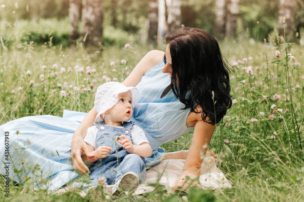 A young mother plays in the park on the grass with her little daughter A young mother plays in the park on the grass with her little daughter