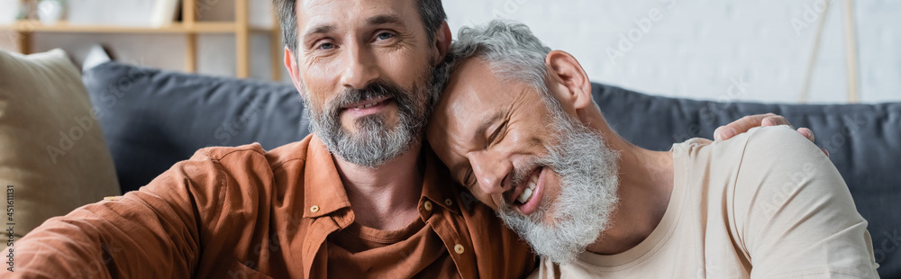 Homosexual man embracing smiling partner at home, banner Homosexual man embracing smiling partner at home, banner