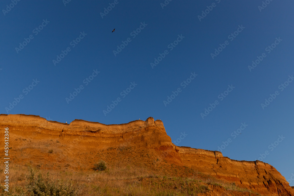 Fototapeta premium Geology. Desert landscape. Panorama view of the sandstone formation, the rocky cliffs, sand. Background or texture of sandy cliff on the coast, orange limestone
