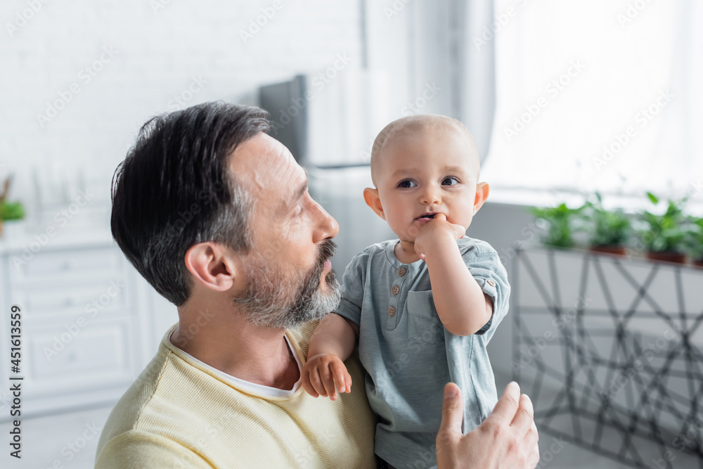 Fototapeta premium Mature parent looking at toddler child at home