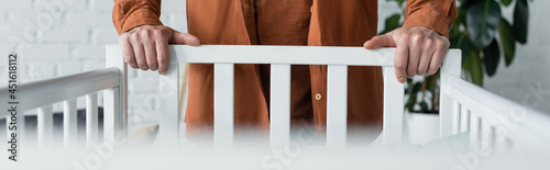 Cropped view of man standing near baby bed, banner