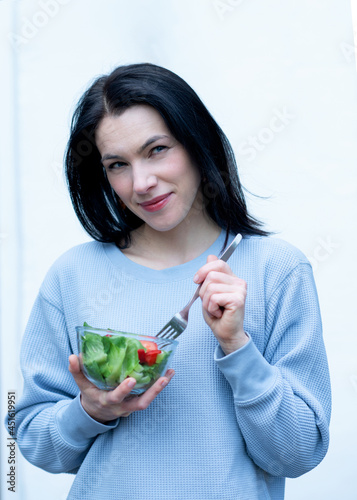 woman holding a folk and bowl with salad and eating in summer