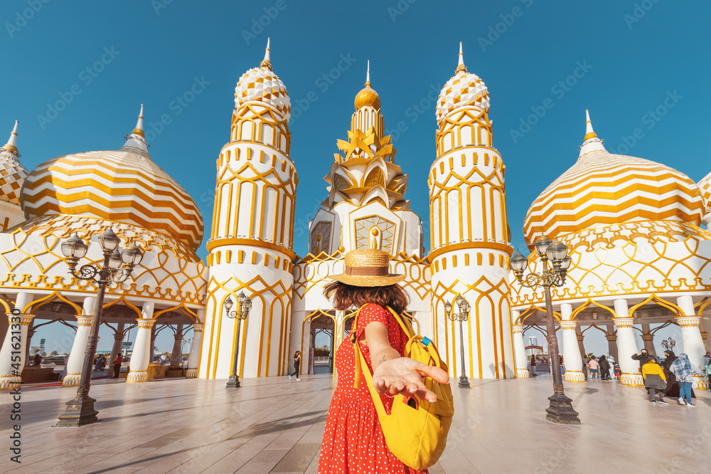 Visitor making follow me pose and panoramic view of the main entrance to the famous multinational exhibition complex Global Village