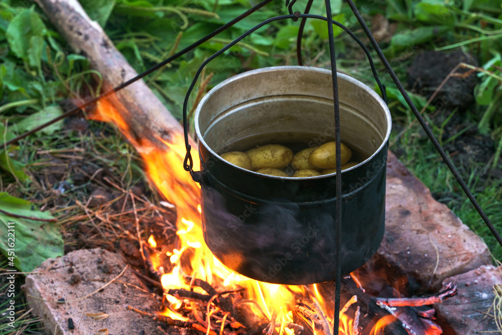 Dixie with potatoes stands on the fire, close-up photo Dixie with potatoes stands on the fire, close-up photo