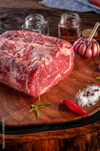 Raw entrecote beef on a wood cutting board with spices.