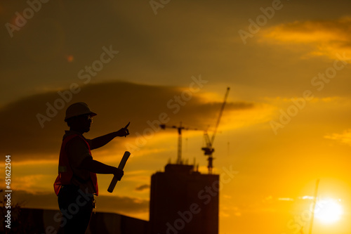 silhouette of engineer and construction site background at sunset