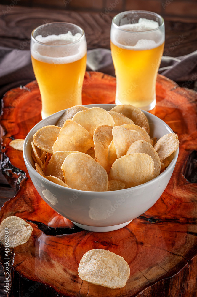 Potato chips in a bowl with two glasses of beer
