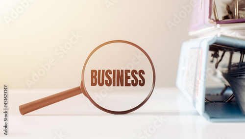 Magnifying glass with the word BUSINESS on office table.