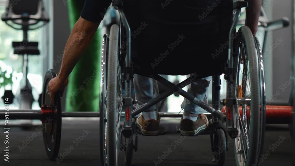 Old person with a disability at the gym preparing weights for exercise Old person with a disability at the gym preparing weights for exercise