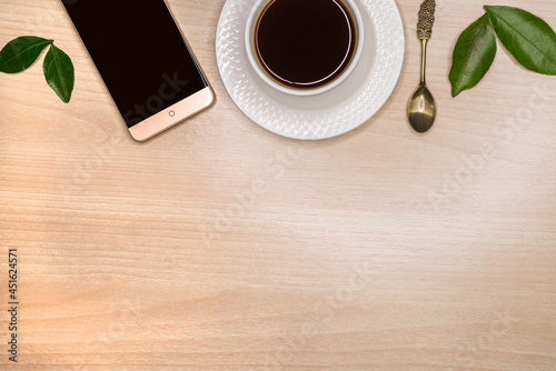 Template for an inscription, on the table lies a smartphone, a mug with coffee and a spoon and a place for an inscription.
