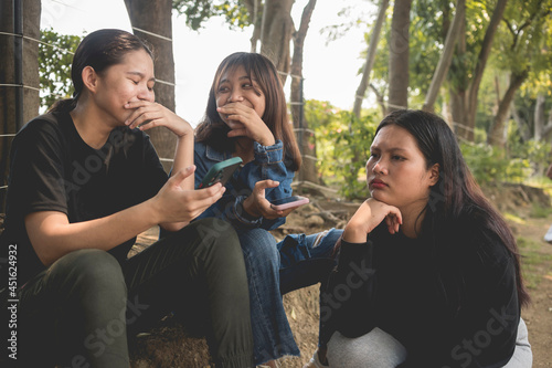 A young teenager woman cannot relate to a conversation her friends are having. Feeling awkward and out of place.