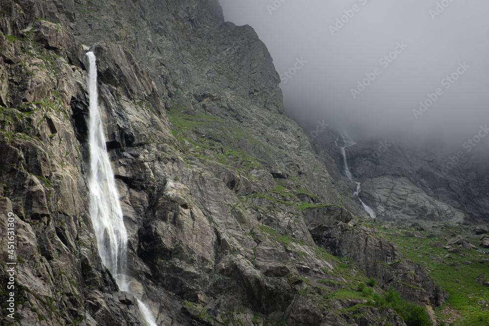 Panoramic landscape Midagrabin waterfalls in sunlight in cloudy summer weather. Caucasus mountains. Russia. North Ossetia Alania