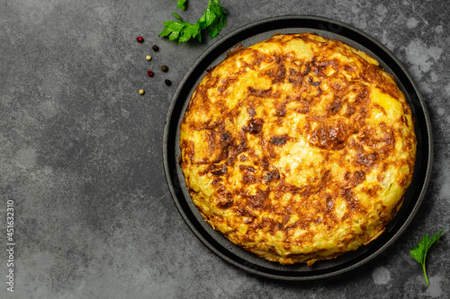 Delicious Spanish tortilla in cast iron skillet, dark background. Space for text, top view.