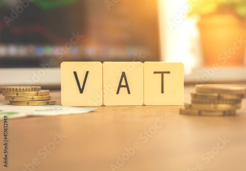 European finance taxation concept background. VAT text and coins on desktop with laptop, business