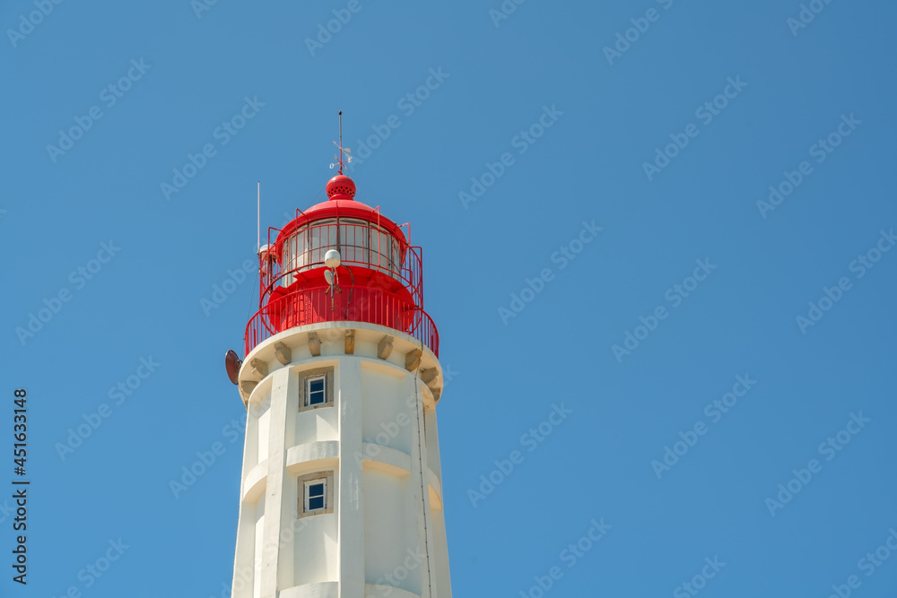A white lighthouse with a red top, against the blue sky. A conceptual signal for the direction of everything. Copy space