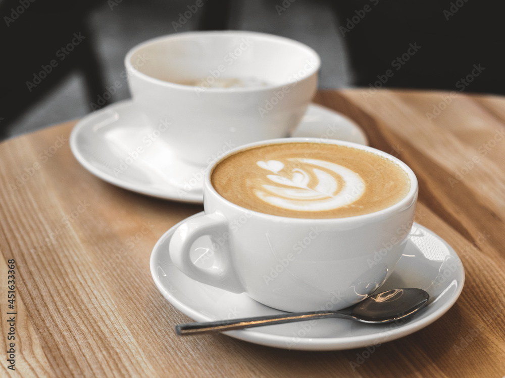Fototapeta premium Cup of coffee with milk on wooden table. Hot Cappuccino or latte prepared with milk in coffee shop. Morning breakfast in cafe. Lifestyle