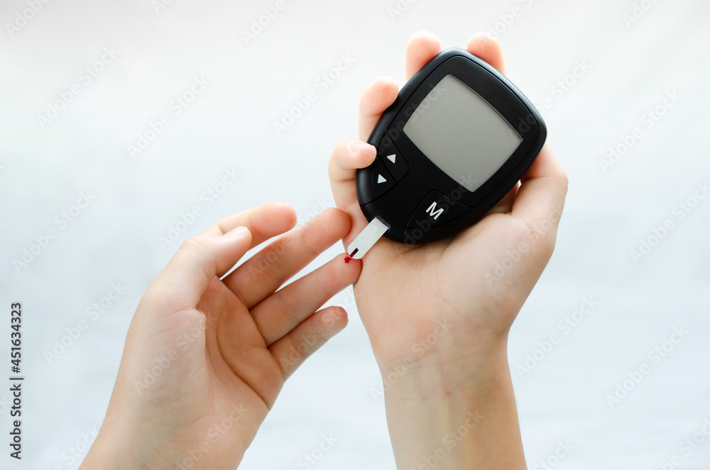 Fototapeta premium Diabetes test. Child hands checking blood sugar level by Glucose meter.