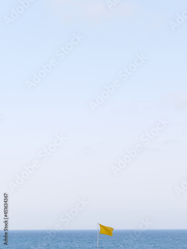 Minimalist photo of a yellow flag with the sea in the background