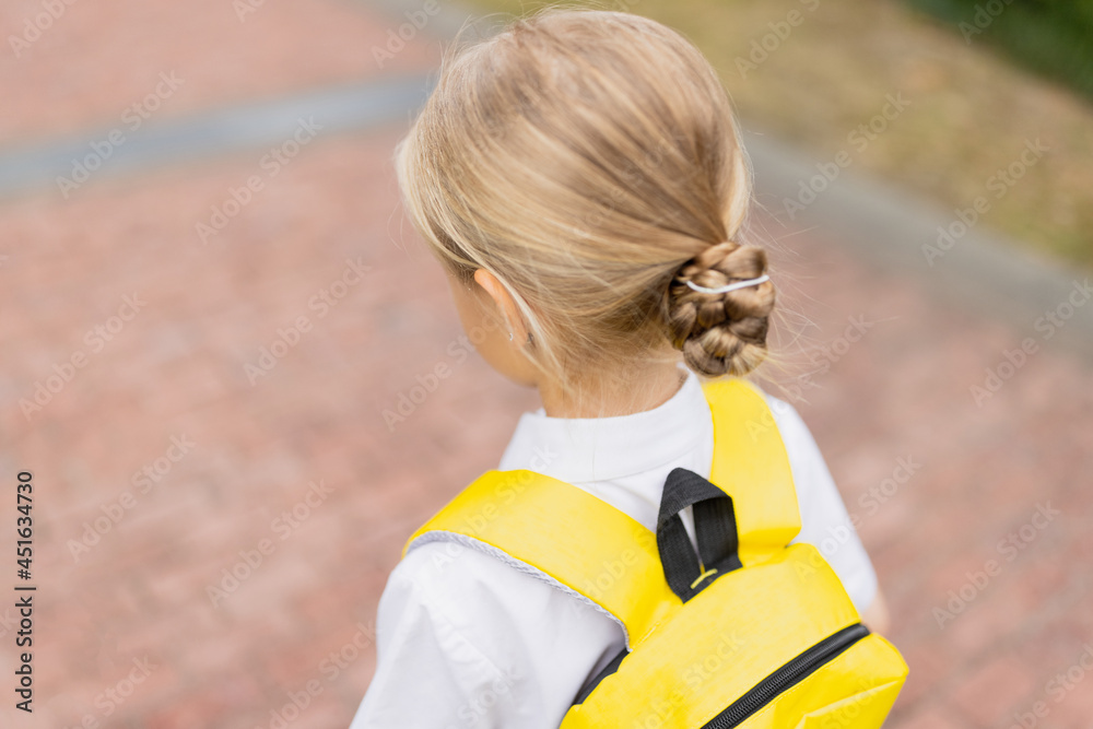 Naklejka premium Schoolgirl back to school after summer vacations. Child in uniform standing early morning outdoor. 