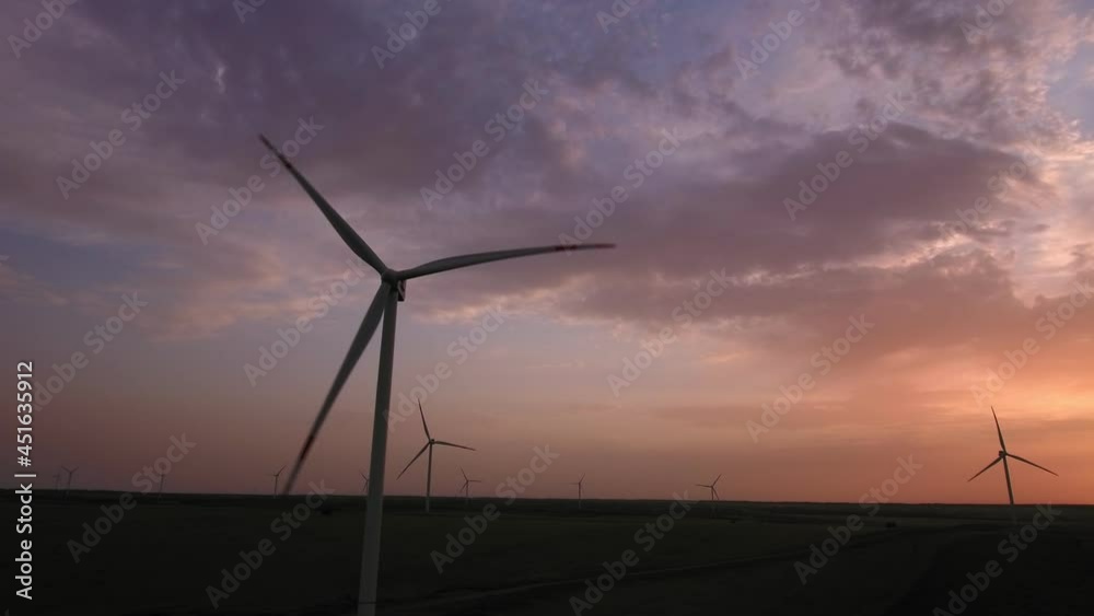 Aerial view. The wind farm is working against the backdrop of a beautiful sunset. Windmill in the process of work. Alternative energy sources. Eco-friendly technologies. Aerial view. The wind farm is working against the backdrop of a beautiful sunset. Windmill in the process of work. Alternative energy sources. Eco-friendly technologies.