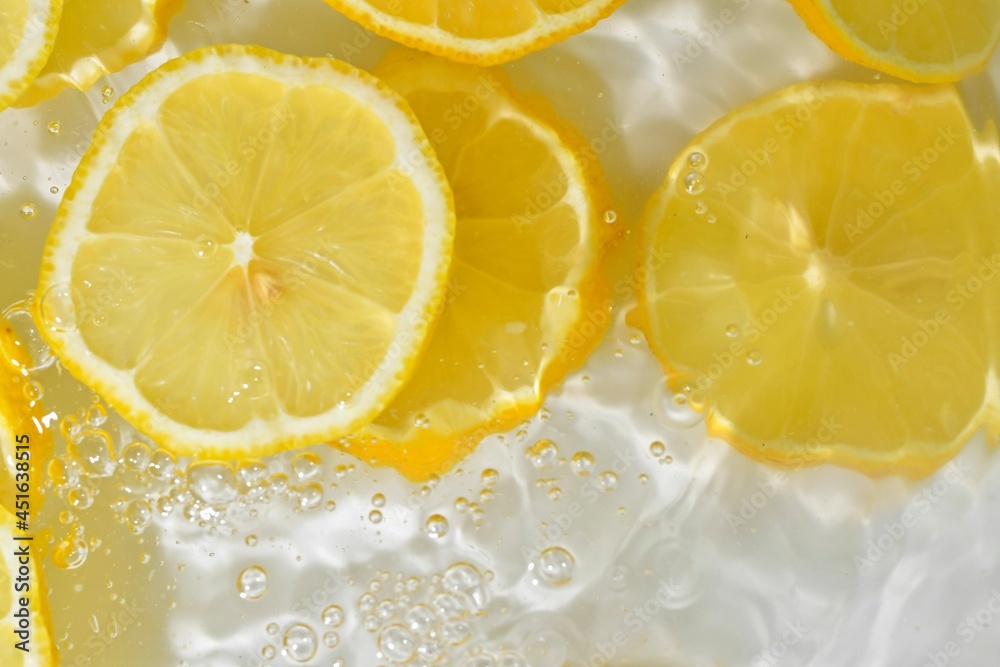 Slices of lemon in water on white background. Lemon close-up in liquid with bubbles. Slices of yellow ripe lemon in water. Macro image of fruits in water Slices of lemon in water on white background. Lemon close-up in liquid with bubbles. Slices of yellow ripe lemon in water. Macro image of fruits in water