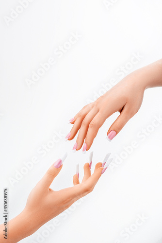 Well-groomed female hands with elegant french manicure on a white background. Long nails. Beauty salon. Photo for the catalog. High quality photo