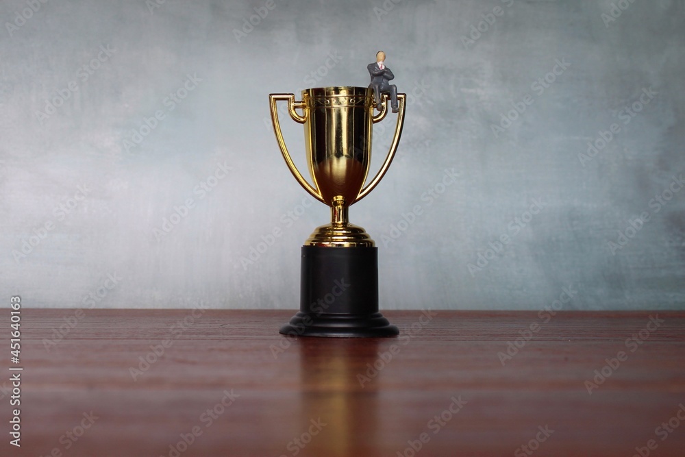 Business concept. Successful businessman sitting on a gold trophy. Selective focus. Copy space for text Business concept. Successful businessman sitting on a gold trophy. Selective focus. Copy space for text