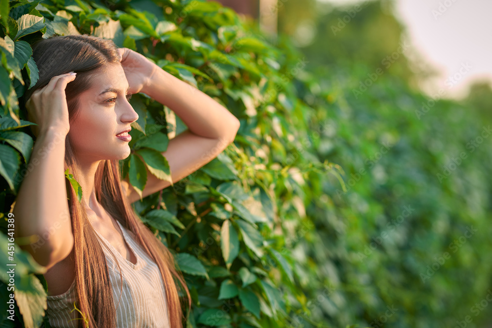 model by a green hedge