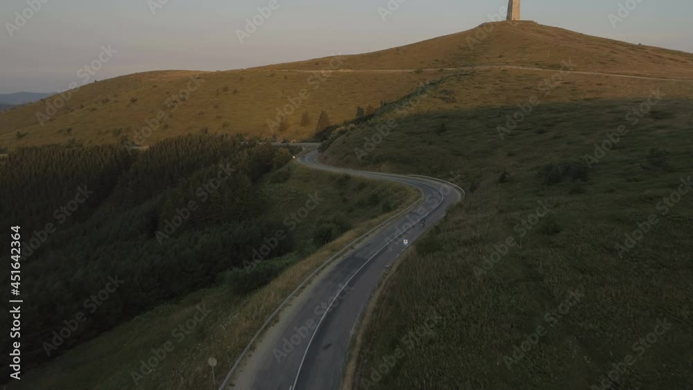 Drone following energetic cyclist speeding down asphalt mountain road at sunset Drone following energetic cyclist speeding down asphalt mountain road at sunset