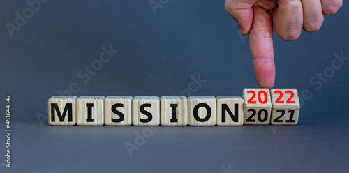 2022 mission and new year symbol. Businessman turns wooden cubes, changes words mission 2021 to mission 2022. Beautiful grey background, copy space. Business, 2022 mission and new year concept.