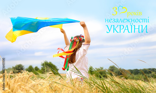 Yellow and blue flag of Ukraine in the hands of a beautiful girl in an embroidered shirt and a wreath with ribbons. Text in Ukrainian 30 years of Ukraine's independence, Banner