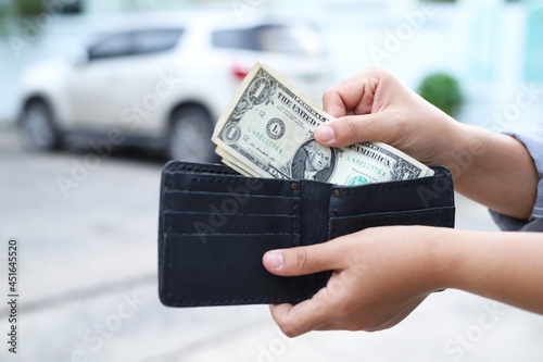 Asian woman pulling money out of a black purse