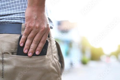 A man is pulling a black purse out of his trouser pocket.