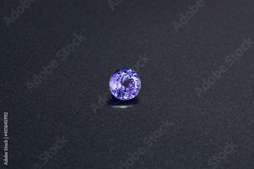 Natural tanzanite gemstone. Round faceted, shaped, transparent, bluish violet color, clean gem setting for making jewelry. Gemology theme. Dark background.  photo