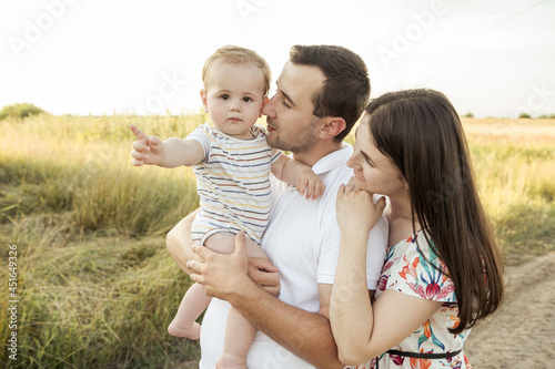 Portrait of young happy family with cute toddler son enjoy sunlight at summer day