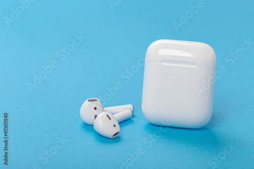 Modern wireless bluetooth headphones with charging case on a blue background. The concept of modern technology, gadgets. Modern wireless bluetooth headphones with charging case on a blue background. 