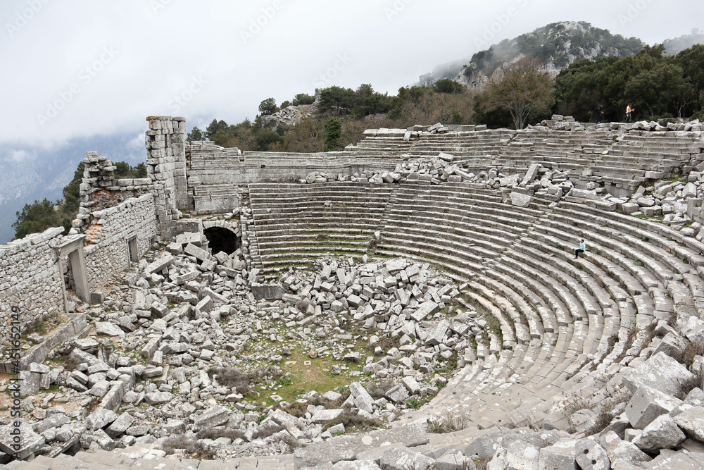 young woman tourist sits alone in the ancient amphitheatre of Termessos in Turkey