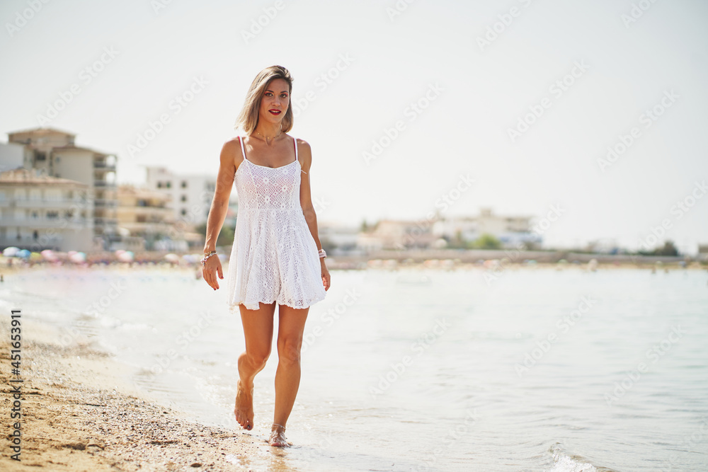 Portrait of hispanic woman walking by the beach with white dress
