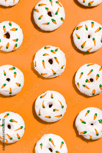 Homemade carrot cake donuts with cream cheese frosting and royal icing carrots on a bright orange background