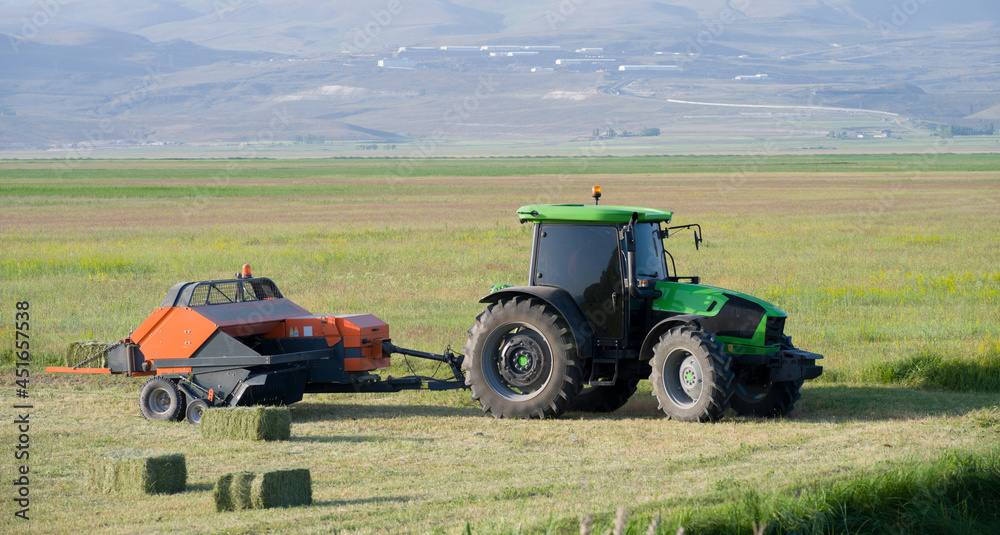 Rectangular baler discharges a straw bale in a field. Straw Harvesting process with tractor
Rectangular baler discharges a straw bale in a field. Straw Harvesting process with tractor
