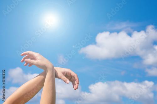 Crossed hands as flying bird with wings gesture.Bird shaped young female hands on bright sunlit blue summer sky, copy space. Concept of freedom,salvation, hope and faith