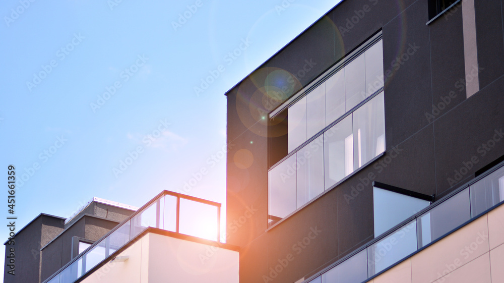 Modern apartment building on a sunny day with a blue sky. Facade of a modern apartment building.Glass surface with sunlight. Modern apartment building on a sunny day with a blue sky. Facade of a modern apartment building.Glass surface with sunlight.
