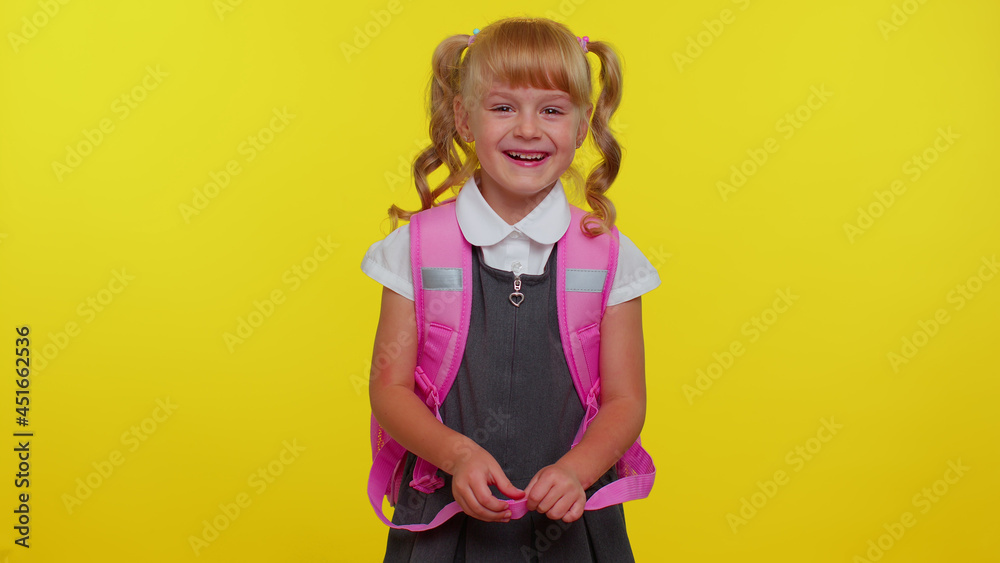 Little cute teen child kid girl in school uniform laughing out loud after ridiculous anecdote, funny joke, feeling carefree amused, positive people lifestyle. Yellow studio background. Back to school