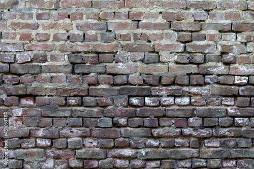 An old brick wall weathered with missing cement joints