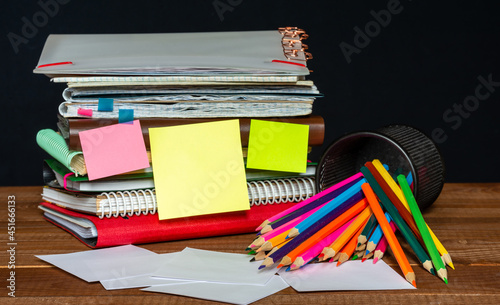 Many different notebooks and folders on the table. Scattered pencils. Stapler. Blank stickers for writing. Work table. Education concept.