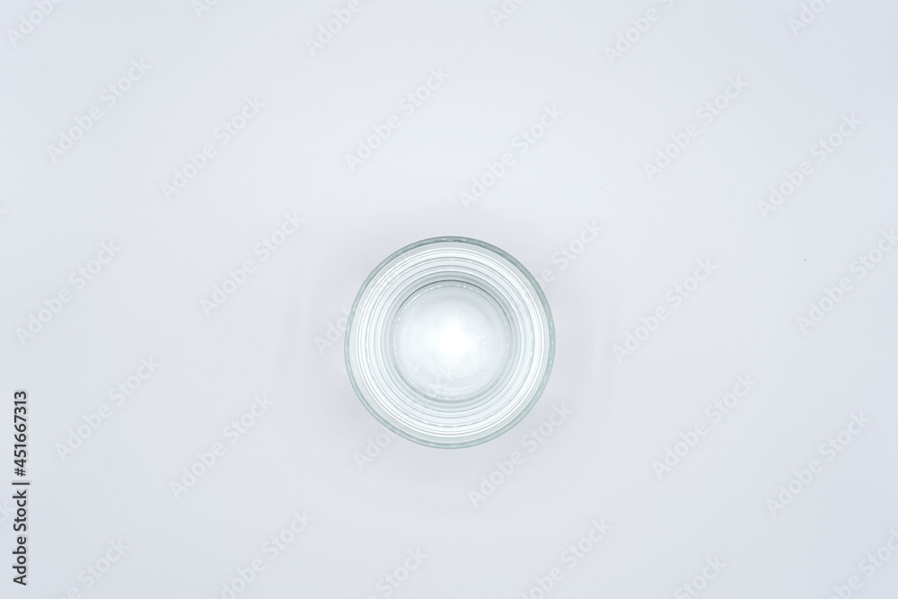 Vaso transparente con agua, vista cenital, fondo blanco.
