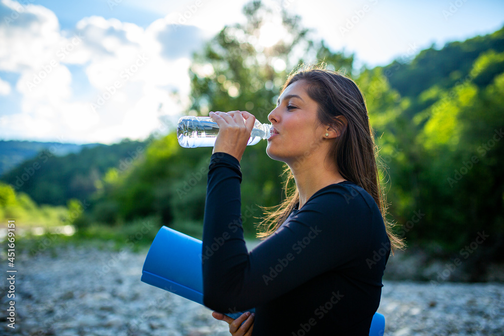 Woman with yoga mat drinking water outdoor Woman with yoga mat drinking water outdoor