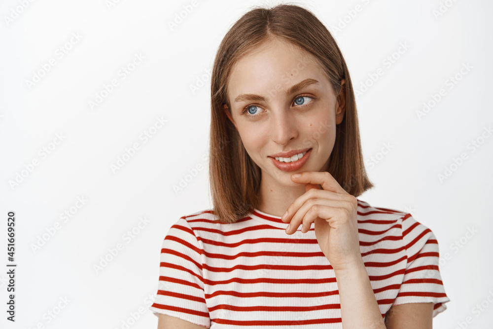 Close up portrait of pretty blond girl, teen student looking aside at promo logo, touch her face and ponder smth interesting, smiling thoughtful, standing over white background Close up portrait of pretty blond girl, teen student looking aside at promo logo, touch her face and ponder smth interesting, smiling thoughtful, standing over white background