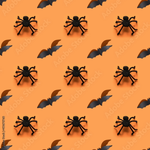 Seamless Halloween pattern of black bat and spiders on orange background. © svetlana_cherruty