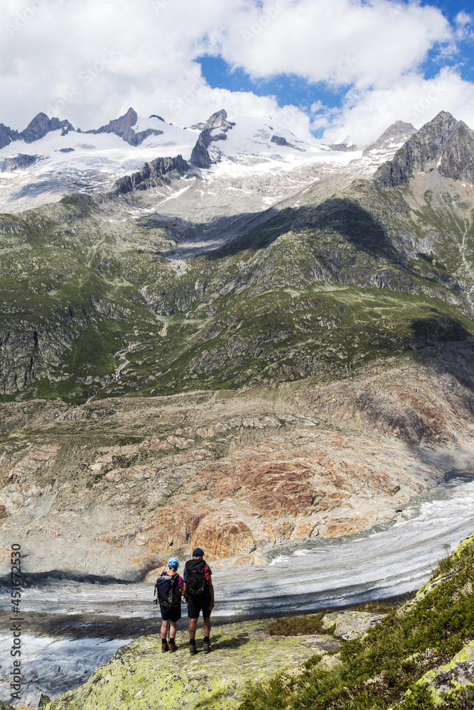 Hikers standing at the edge of the Aletsch Glacier marveling at the wonderful landscape in the region.